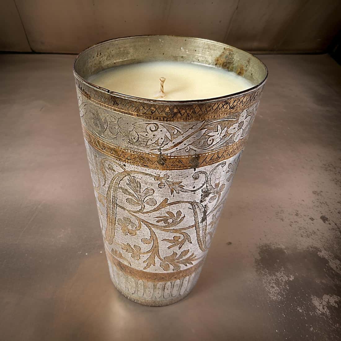 Decorative candle in an ornate metal holder on a plain background