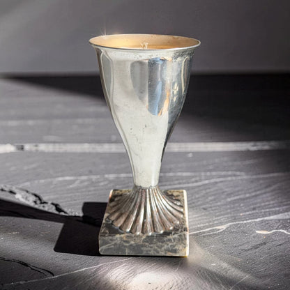 Silver candle holder on a textured surface with a dark background