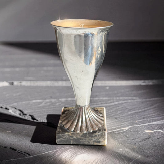 Silver candle holder on a textured surface with a dark background