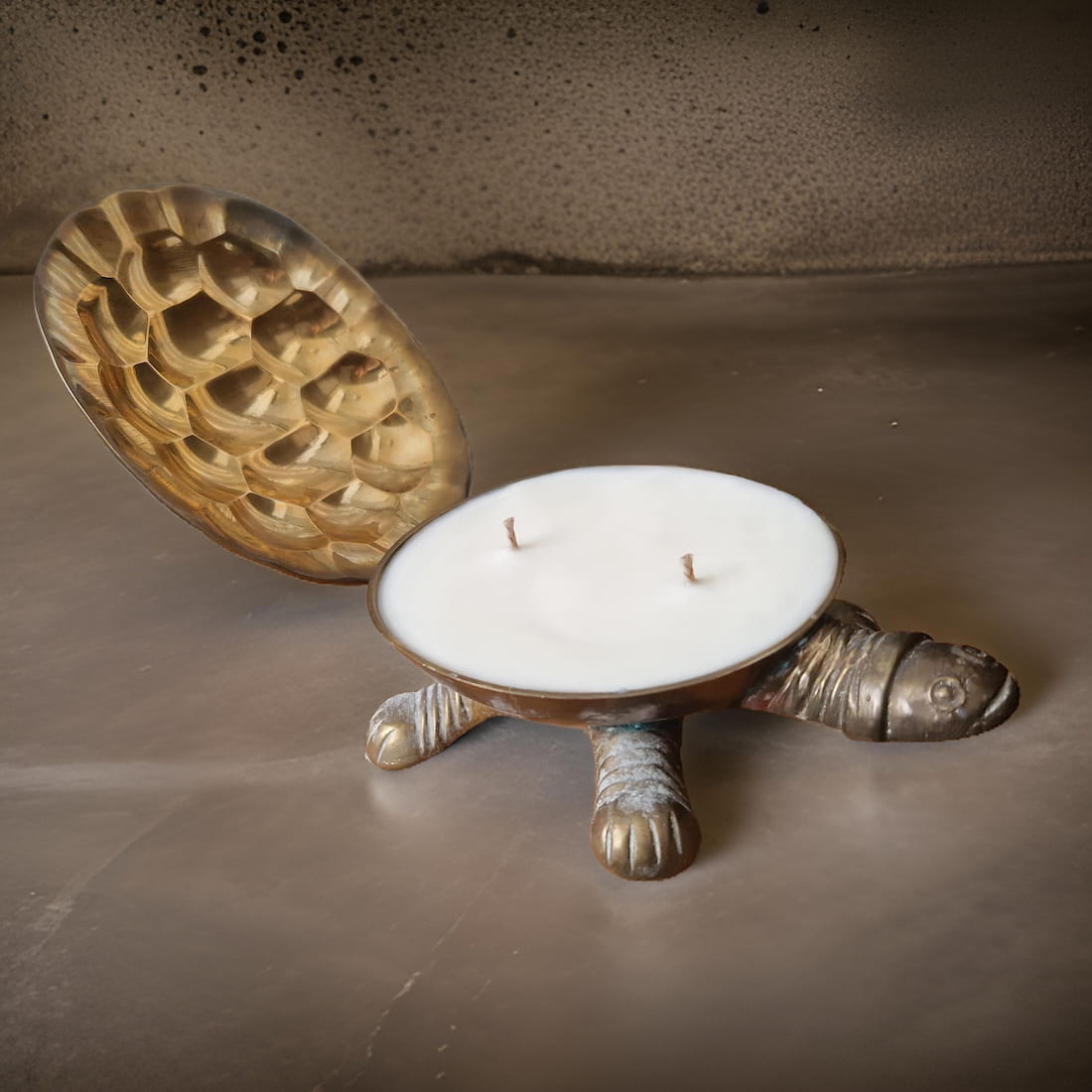 Tortoise-shaped candle holder with a candle inside on a textured surface