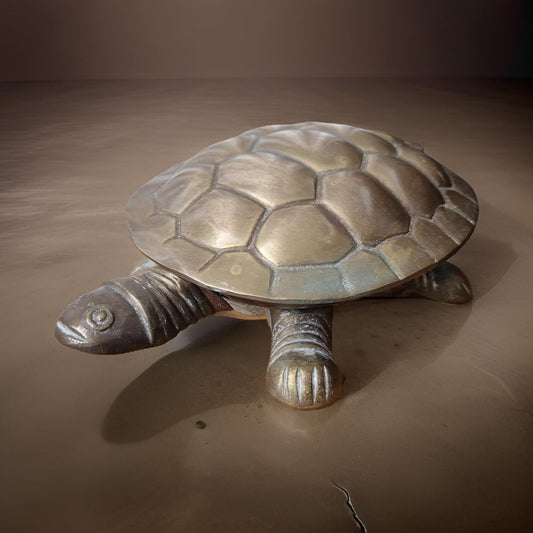 Bronze turtle sculpture on a brown surface