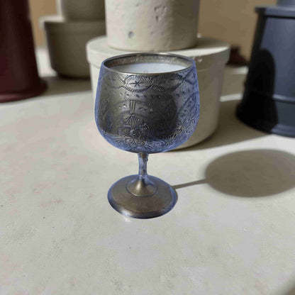 Decorative silver goblet on a light surface with blurred background