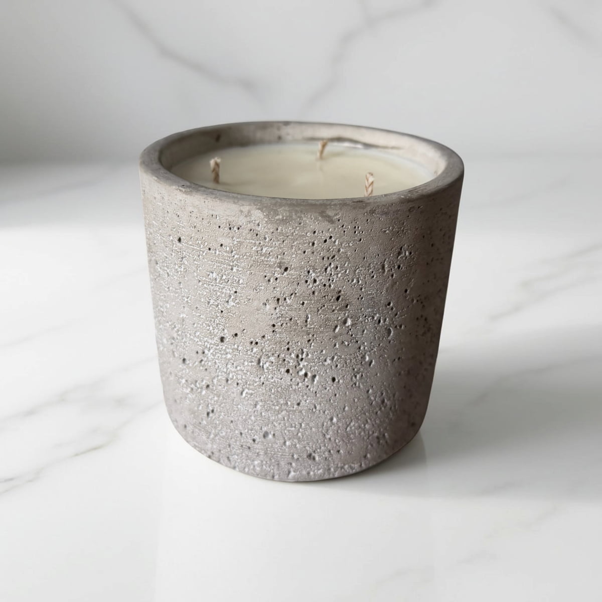 Concrete candle holder with a white candle on a light gray background