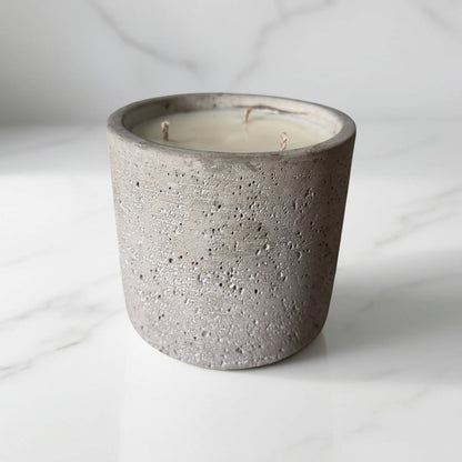 Concrete candle holder with a white candle on a light gray background