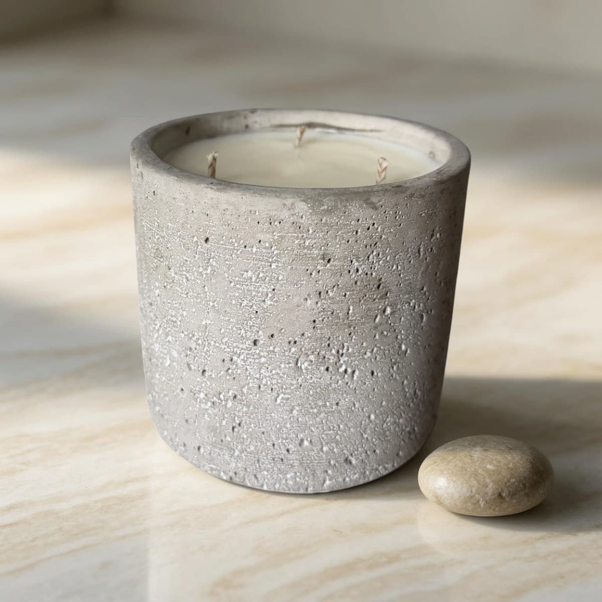 Cement-textured candle in a pot on a light wooden surface