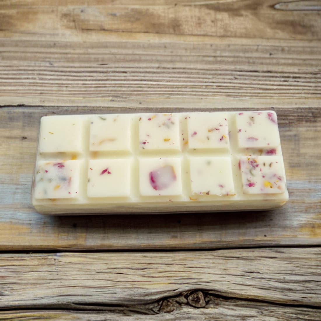 Block of white wax with small colorful pieces on a wooden surface