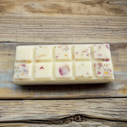 Block of white wax with small colorful pieces on a wooden surface