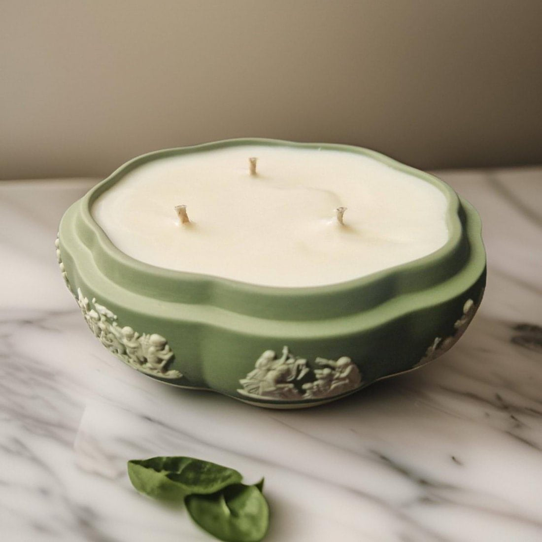 Decorative candle in a green container on a marble surface